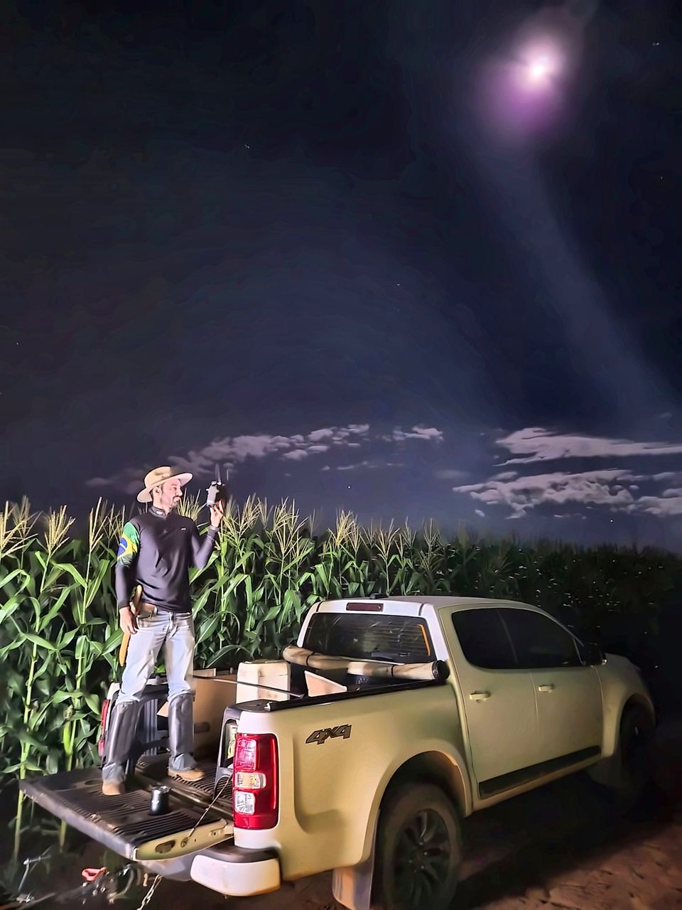 Piloto da Skycrop preparando o drone Agras T25 em lavoura de milho, à noite, no Tocantins